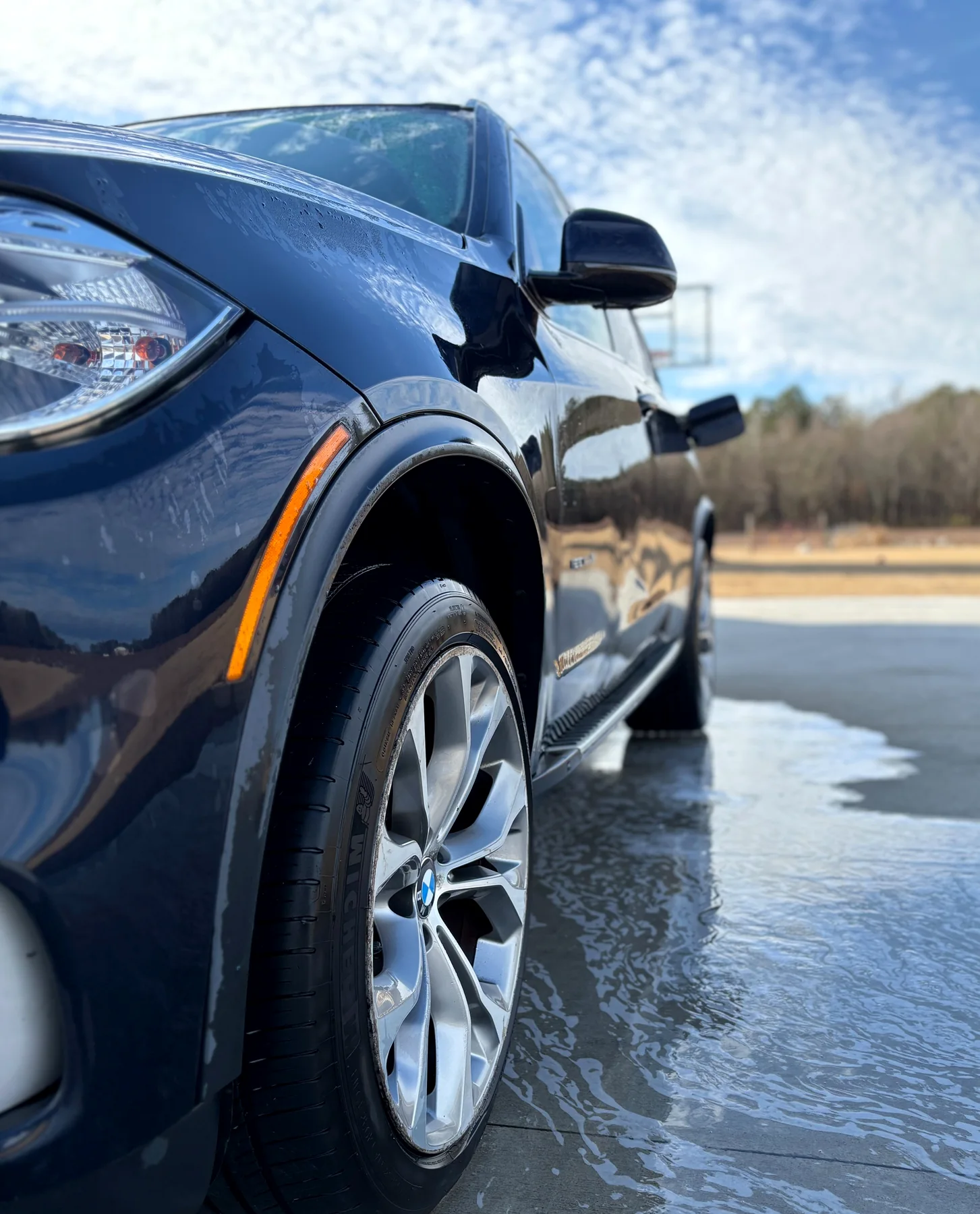 Blue BMW being rinsed in a Greenville driveway
